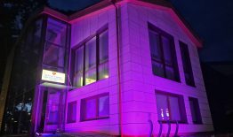 Purpurine spalva nušvito Birštono pirminės sveikatos priežiūros centro pastatas ir prie Savivaldybės pastato esantis užrašas #BIRŠTONAS